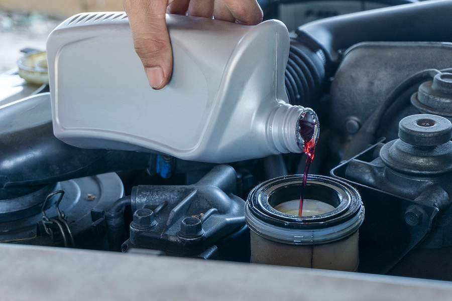 Hand pouring liquid into car engine