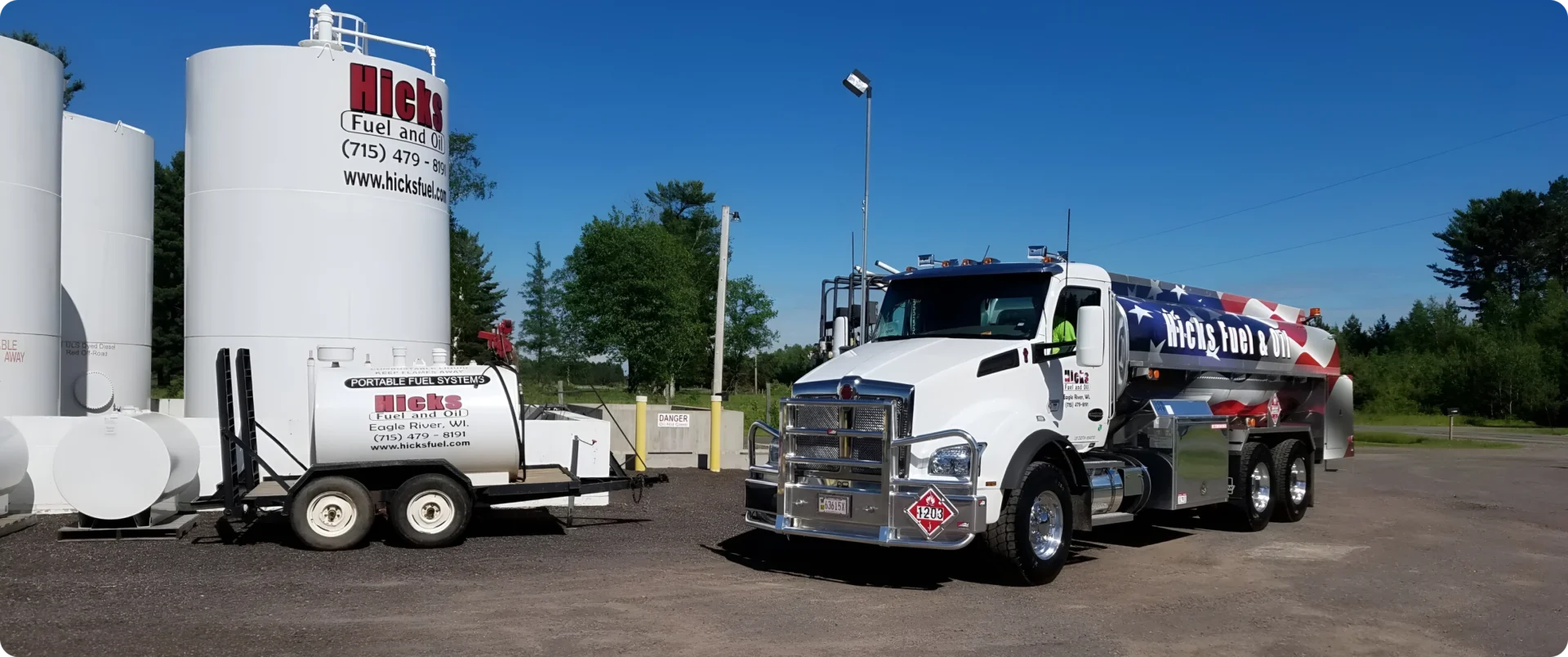 American flag-themed truck beside storage tanks.